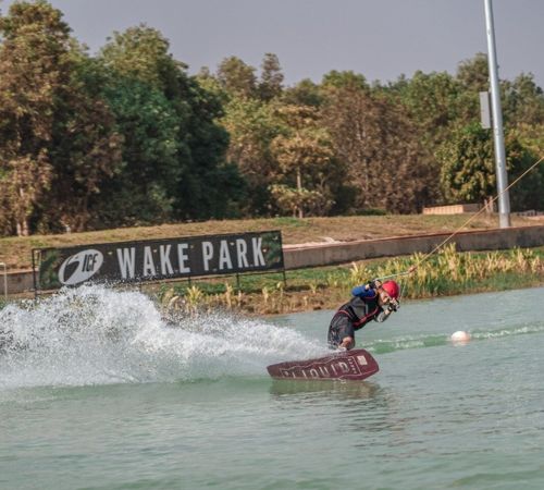 A person wakeboarding and carving through the water at ICF Wake Park near Blanc Smith Hotel in Siem Reap.