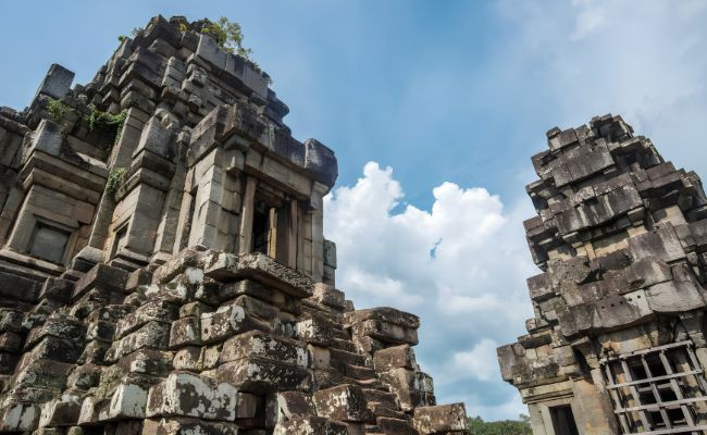 Ancient stone towers of Phnom Bakheng temple under a blue sky during a sunrise small circuit tour in Siem Reap.