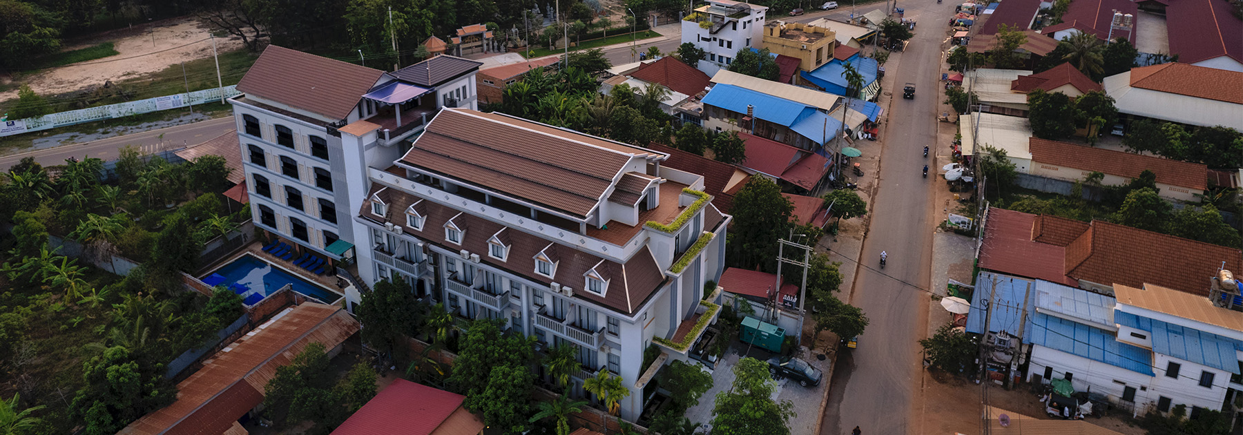 Aerial drone view of Blanc Smith Hotel building architecture and Siem Reap city skyline during sunset.