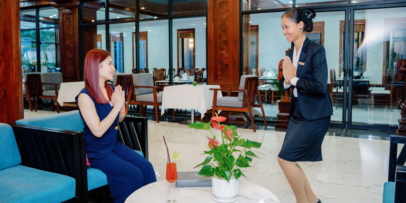 Hotel lobby staff welcoming a seated guest with traditional Sampeah greeting at Blanc Smith Hotel in Siem Reap.